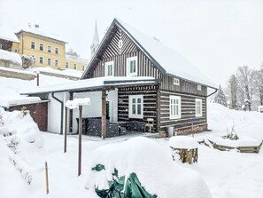 Ein Holzhäuschen mit steilem Dach, umgeben von Schnee.