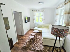 A living room with a sofa, a television, a patterned floor lamp, and a fluffy rug. - Vacation home Sára by Interhome (Janské Lázně)