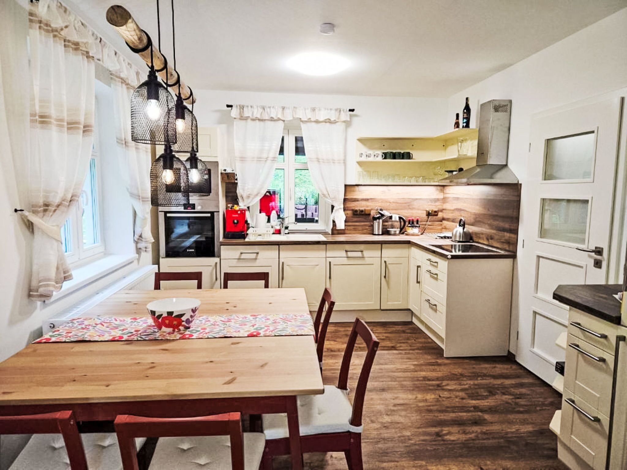 A compact kitchen with a dining table, chairs, and a TV.