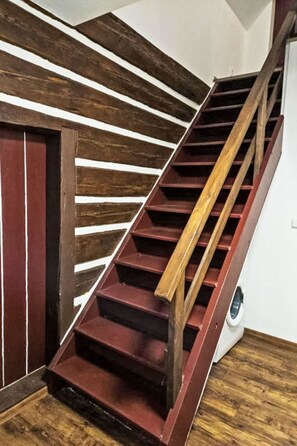 A wooden staircase with a handrail and a red door. - Vacation home Sára by Interhome (Janské Lázně)