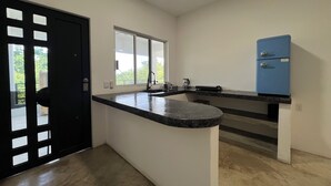Eine Küche mit schwarzem Arbeitsplatz, einem Fenster und einem blauen Kühlschrank.