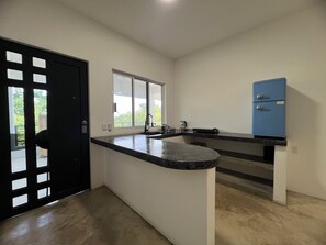 Eine Küche mit schwarzem Arbeitsplatz, einem Fenster und einem blauen Kühlschrank.