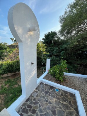 A white outdoor structure with a stone-tiled floor and a door. - Casa Valencia. Two Studios residence. Fully equipped for comfort and connection. (Barra de Navidad)
