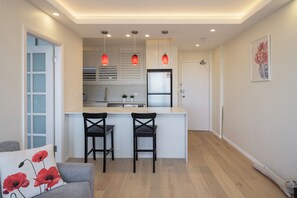 Eine moderne Küche mit zwei Barhocker, einem Kühlschrank und Pendelleuchten.