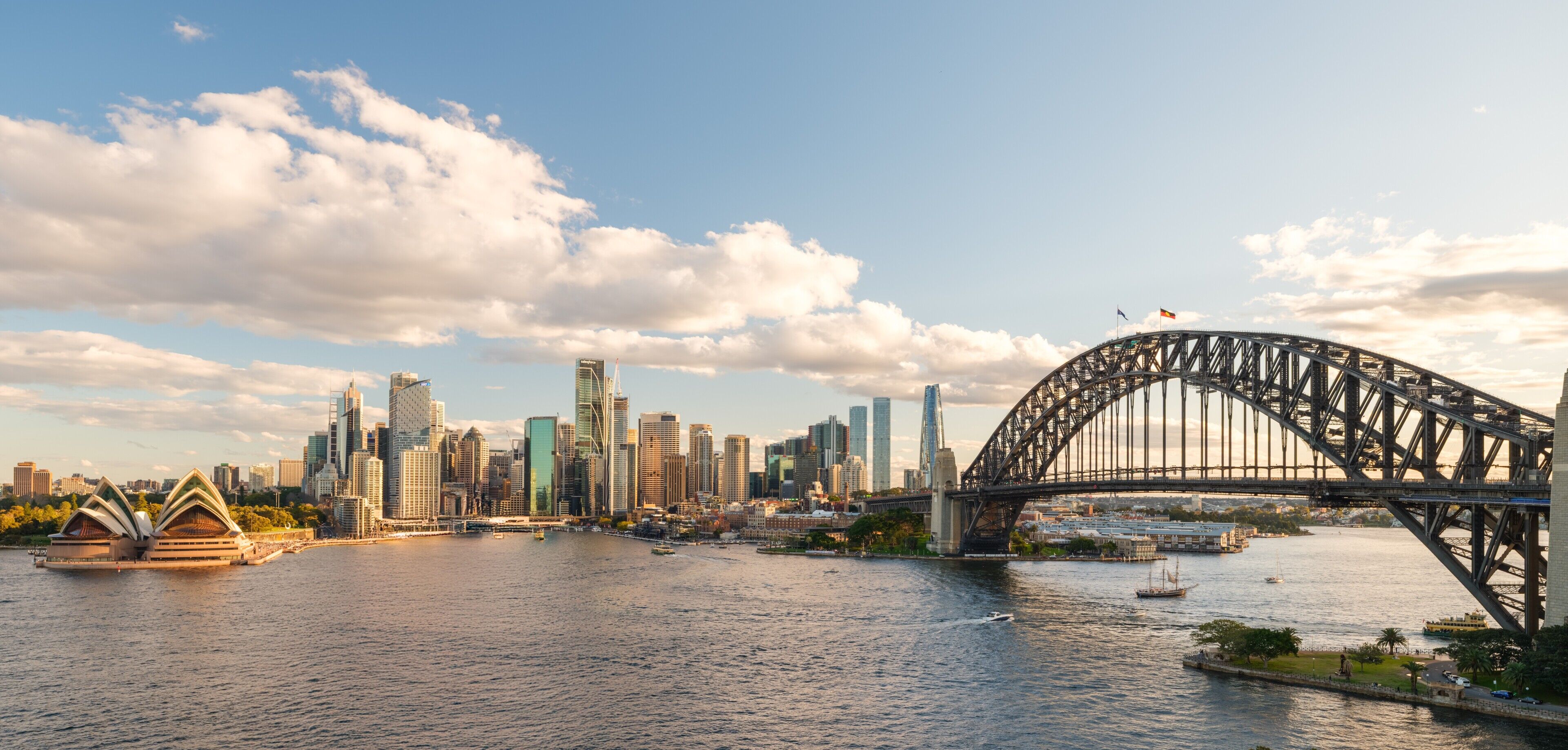 A cityscape with a prominent bridge and the Sydney Opera House.