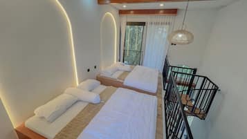 A modern bedroom with two beds, a wooden ceiling, and a view of the outdoors.