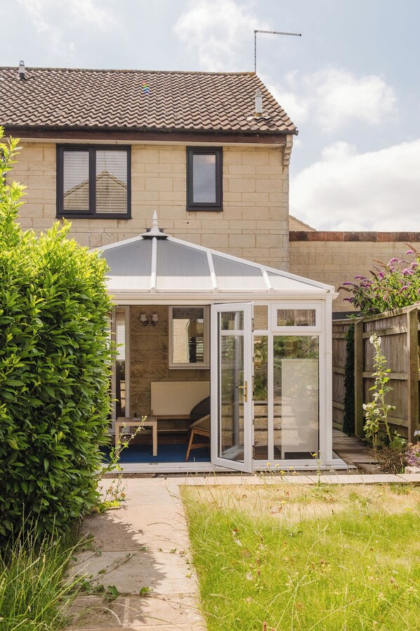 A house with a covered patio area, a visible window, and a garden.