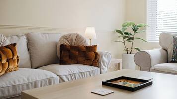 Ein Wohnzimmer mit Sofa, Couchtisch, Lampe und Topfpflanze.