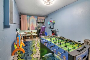 A room with a foosball table, a colorful rug, and a wall with a cityscape mural. - Casa de sueños -king of kings (Clermont)