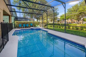 An indoor swimming pool with a glass enclosure, surrounded by a patio area with chairs and a view of a residential neighborhood. - Casa de sueños -king of kings (Clermont)