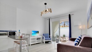 Un soggiorno moderno con una TV a schermo piatto, un'area pranzo con tavolo e sedie, un divano e una lampada a sospensione.