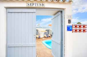 Entrada de hotel con un letrero que dice 'NEPTUNO' y el número '15' en la pared.