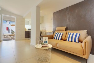 Una sala de estar moderna con un sofá color beige, una mesa de centro redonda y un comedor al fondo.