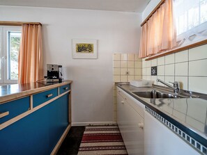 A compact kitchen with a coffee machine, a sink, and a window with curtains. - Chesa Quadrellas / OG by Interhome (Samedan)