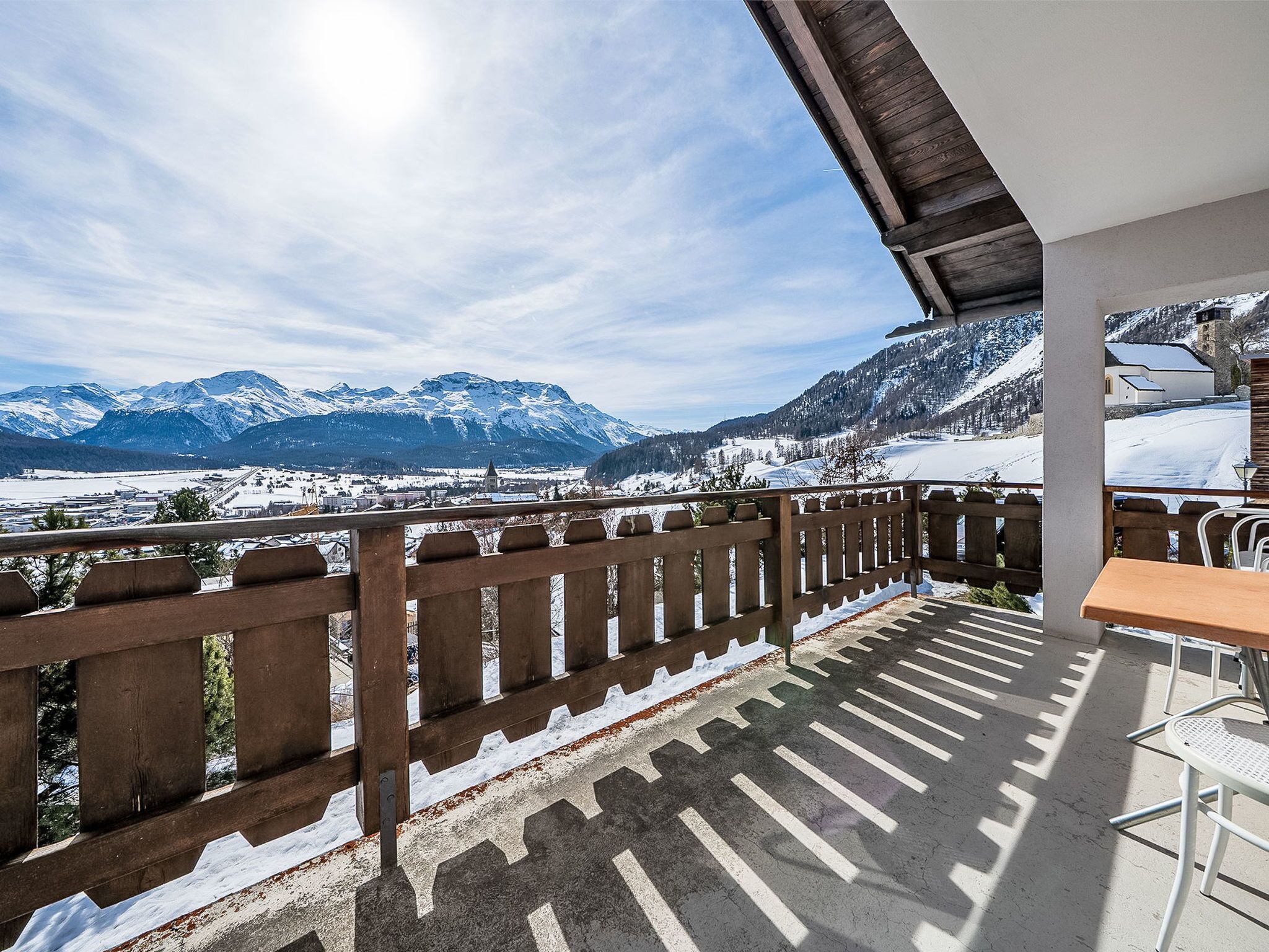 A balcony with a view of snow-covered mountains and a clear sky.