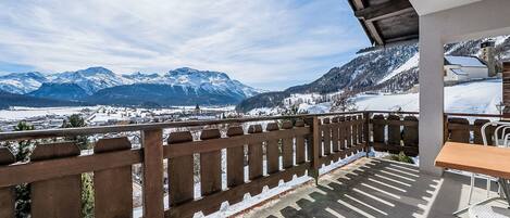 A balcony with a view of snow-covered mountains and a clear sky.