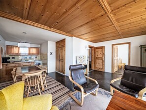 A spacious living area with a wooden ceiling, a dining table with chairs, a sofa, and a rug. - Chesa Quadrellas / OG by Interhome (Samedan)