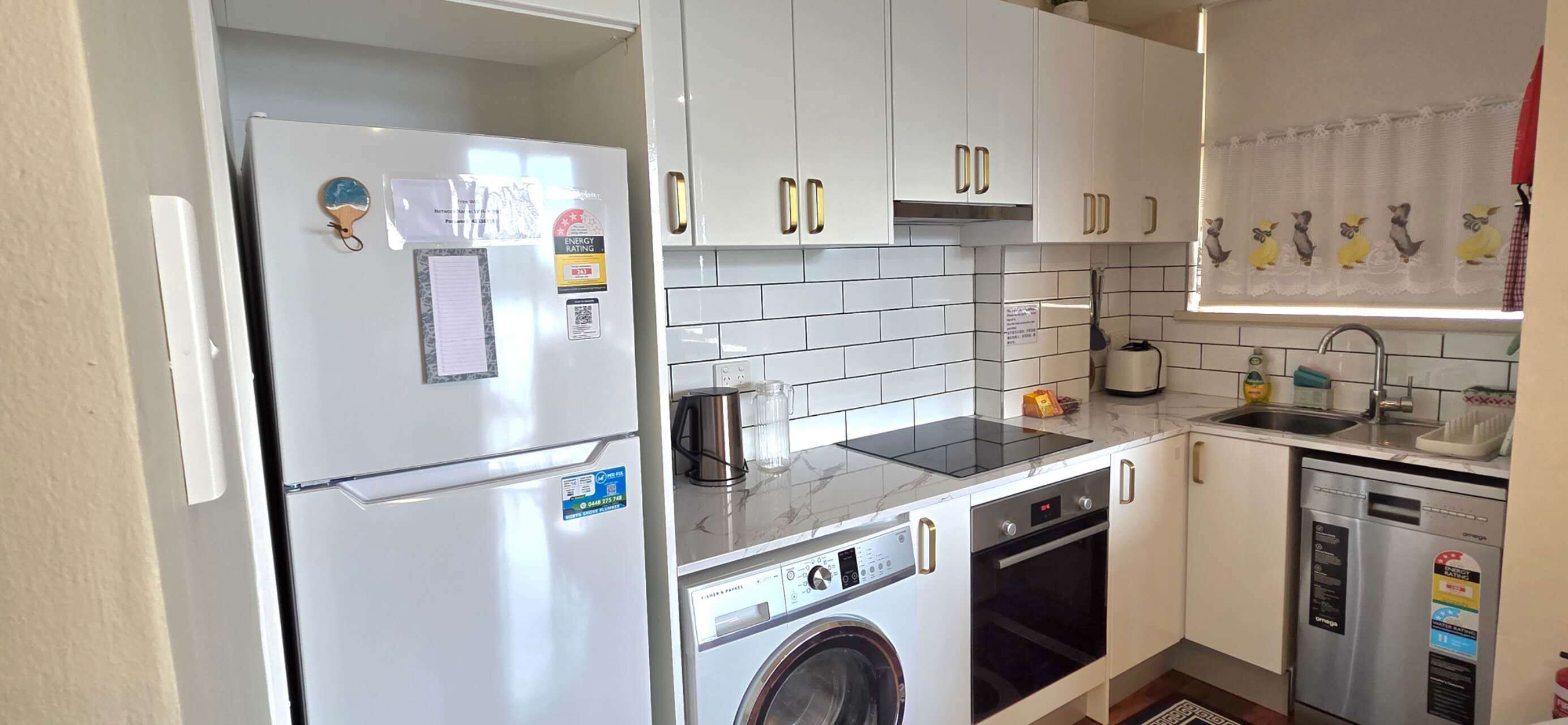 A compact kitchen with a refrigerator, stove, oven, dishwasher, and washing machine.