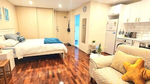 Hotelkamer met een bed, een slaapbank, een bureau, een stoel, een kledingkast, een badkamer en een kitchenette.
