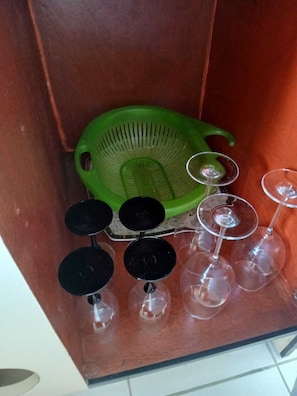 A kitchen cabinet with a green colander and several wine glasses. - Quiet family home – 10 min from Folle Anse Beach, Marie-Galante (GRAND-BOURG (97112))
