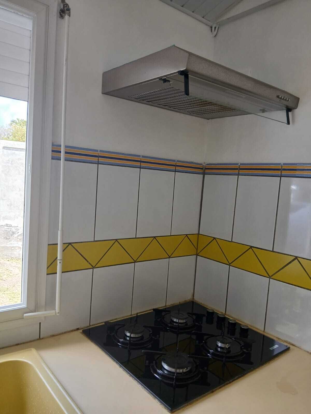 Une cuisine équipée d’une cuisinière à gaz, d’une hotte aspirante et d’une fenêtre.