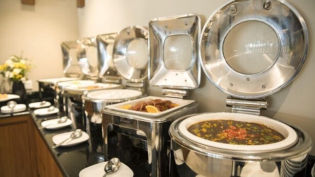 Montaje de bufé con varios recipientes de comida y utensilios para servir.