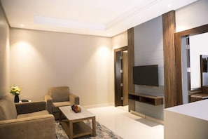 A modern living room with a flat-screen TV, a sofa, a coffee table, and a decorative vase. - Swiss Blue Heraa (Jeddah)