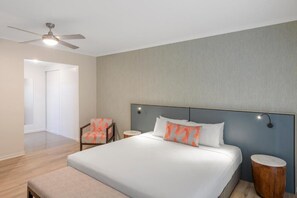 Ein Hotelzimmer mit Bett, Deckenventilator, Stuhl und Nachttisch.