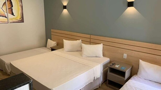 Ein Hotelzimmer mit zwei Betten, einem Holzkopfteil, Nachttischen und Wandleuchten.