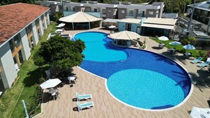 A hotel with a large outdoor swimming pool, lounge chairs, and umbrellas. - Porto Mar Hotel Porto Seguro (Porto Seguro)