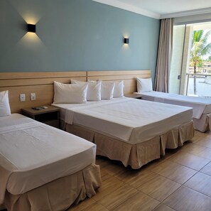 A hotel room with two beds, a wooden headboard, a nightstand, and a window with curtains. - Porto Mar Hotel Porto Seguro (Porto Seguro)