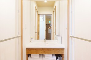Une salle de bain avec un meuble-lavabo en bois, un miroir et un porte-serviettes.