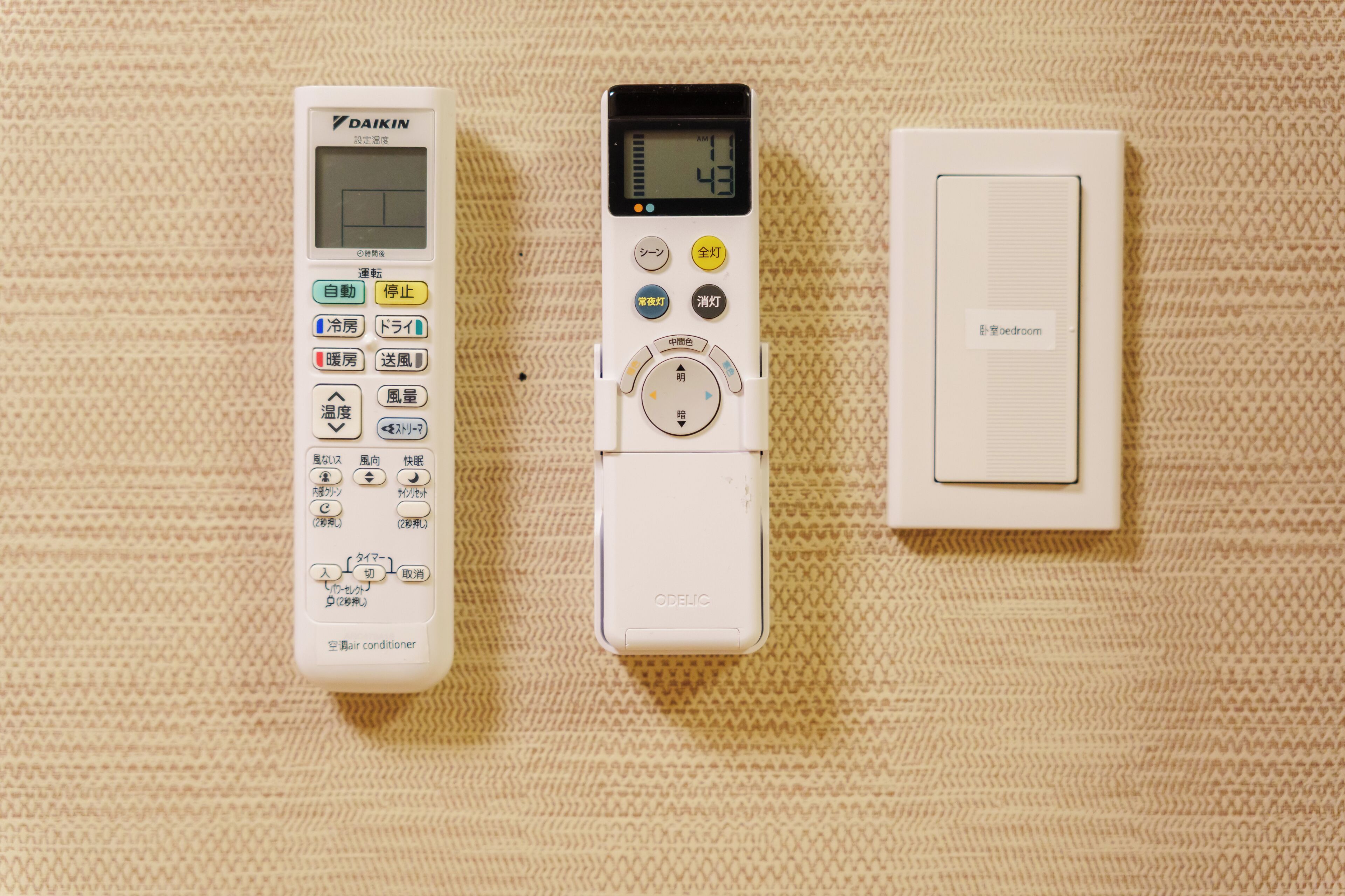 Trois appareils : un thermostat, une horloge numérique et un panneau de commande pour la pièce.