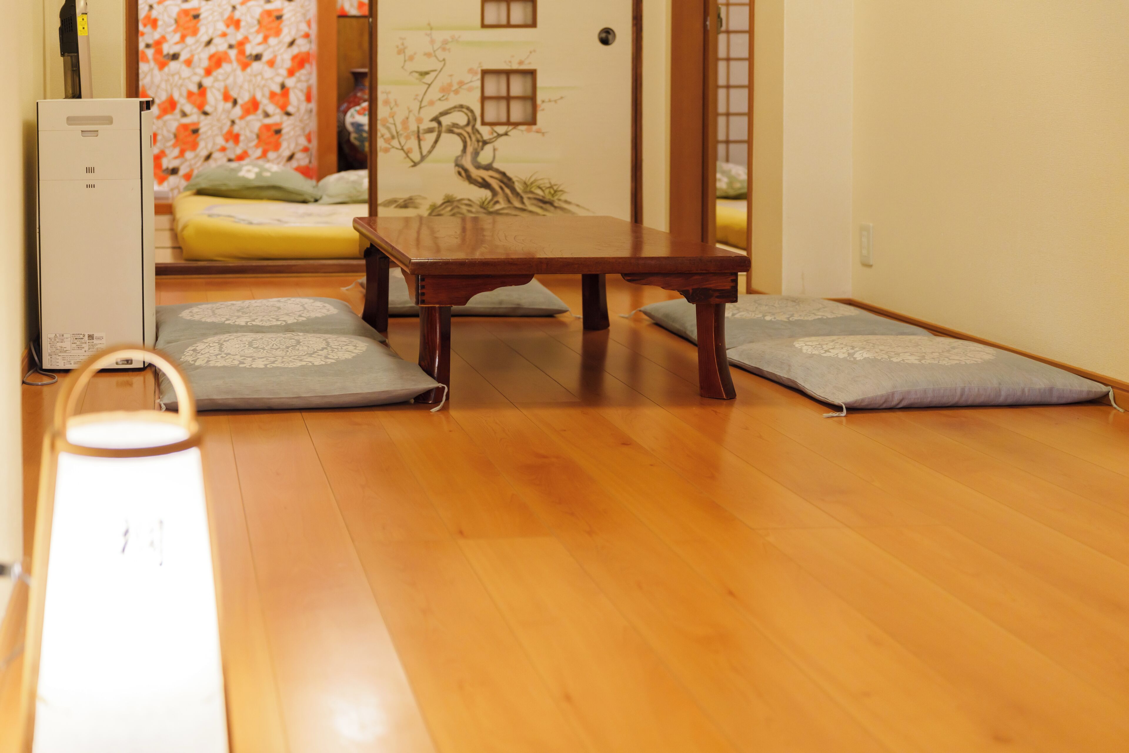 A room with a wooden floor, a table, and two cushions.