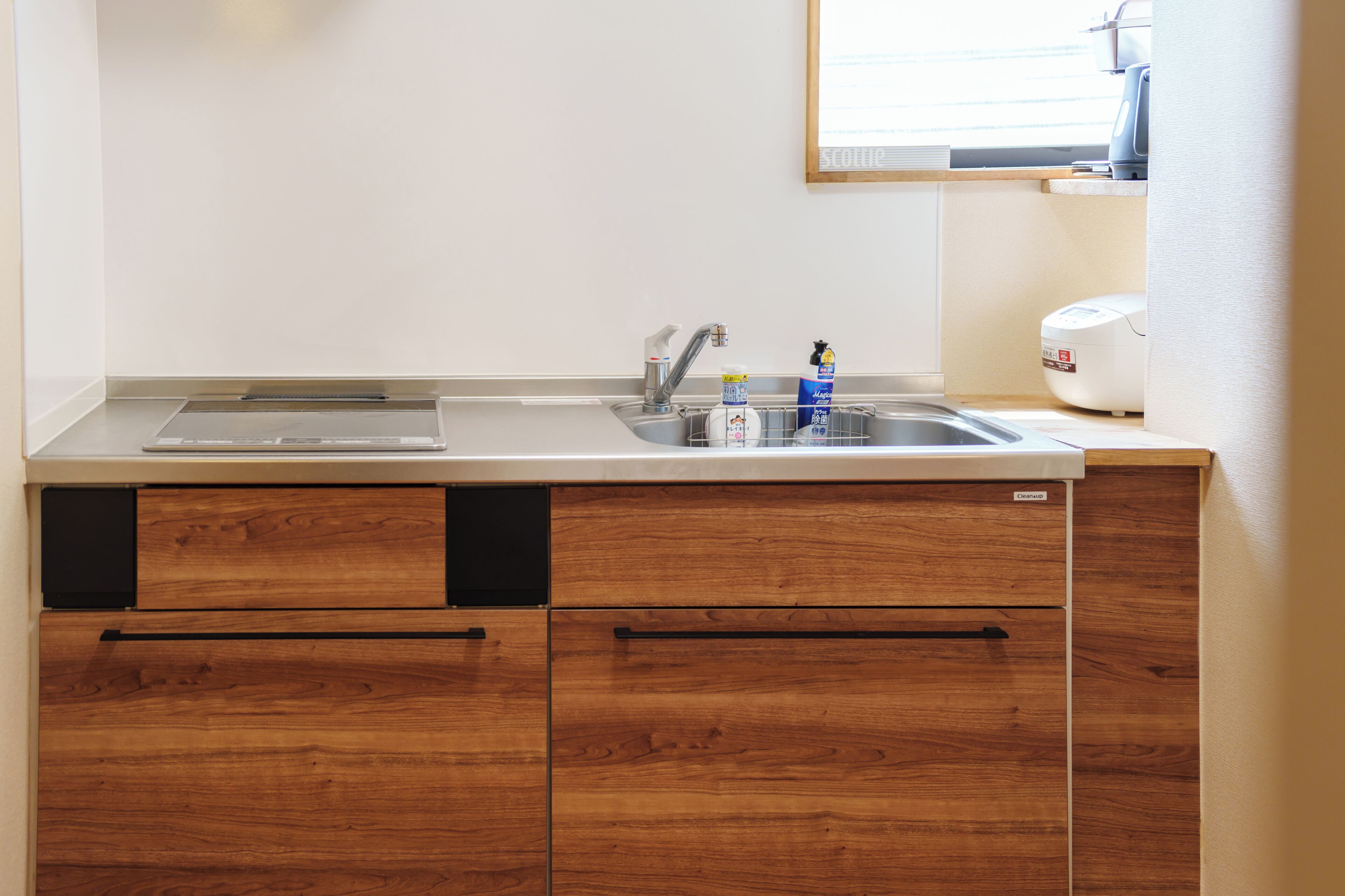 A kitchen with a double sink, wooden cabinets, and a built-in dishwasher.