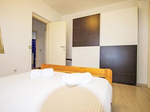 Habitación de hotel con cama, cabecera de madera, armario y puerta.