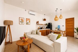 Un salon moderne comprenant un canapé, une table à manger et un coin cuisine.