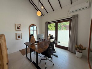 A modern office space with a wooden desk, office chair, and a large window with curtains.