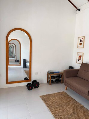 A living room with a large mirror, a brown sofa, a small wooden table, and a woven rug.