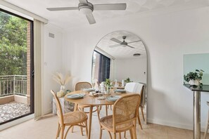 Ein Essbereich mit einem runden Tisch, Korbstühlen und einem Deckenventilator.