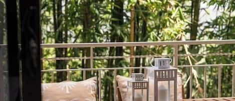 A wooden deck with a table and benches, surrounded by lush greenery.