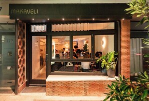 Ein Restaurant mit Ziegelaußenwand, großen Fenstern und sichtbarer Innenbestuhlung.