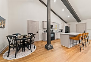 A modern kitchen with white cabinets, a black refrigerator, and a central island with bar stools. - Lakefront 7BR, 7BA Retreat with Pool, Hot tub, Game room, and Private dock. (Hot Springs)