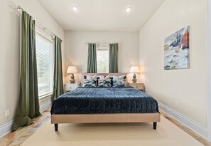 A bedroom with a bed, two bedside tables, a nightstand, a painting, and a window with curtains. - Lakefront 7BR, 7BA Retreat with Pool, Hot tub, Game room, and Private dock. (Hot Springs)