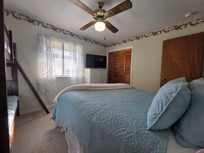 A bedroom with a bed, a ceiling fan, a television, a wardrobe, and a window with curtains. - Coral Cottage! Steps to Pool From Back Door! (Panama City Beach)