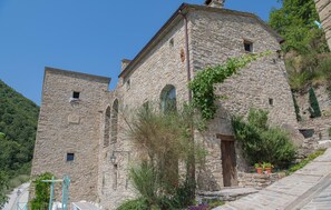Ein Gebäude aus Stein mit traditioneller Architektur, das einen zentralen Turm und Rundbogenfenster zeigt.