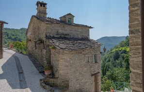 A stone building with a sloped roof, a small window, and a door. There are potted plants on the ground. - 1 bedroom lovely home in Badia Tedalda, Loc. Ac (Badia Tedalda, Loc. Ac)