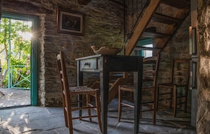 Ein rustikaler Raum mit Steinwänden, einem Holztisch mit einer Schüssel und zwei Korbstühlen.