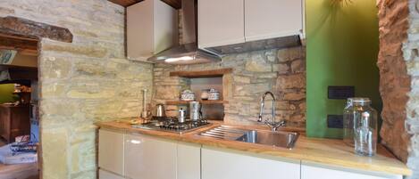 A kitchen with a stone wall, wooden ceiling, and a built-in sink.