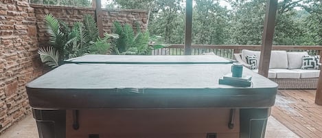 Un jacuzzi con escalones de acceso, rodeado por una terraza de madera y un muro de piedra.